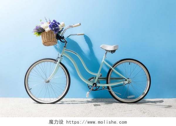 蓝色墙壁前面篮子的自行车的侧面与花